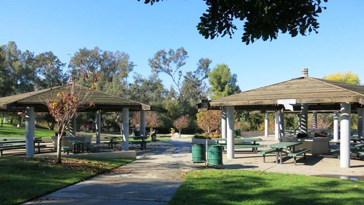 Garvey Ranch Park with green lawn, trees, and a pathway under a sunny blue sky.