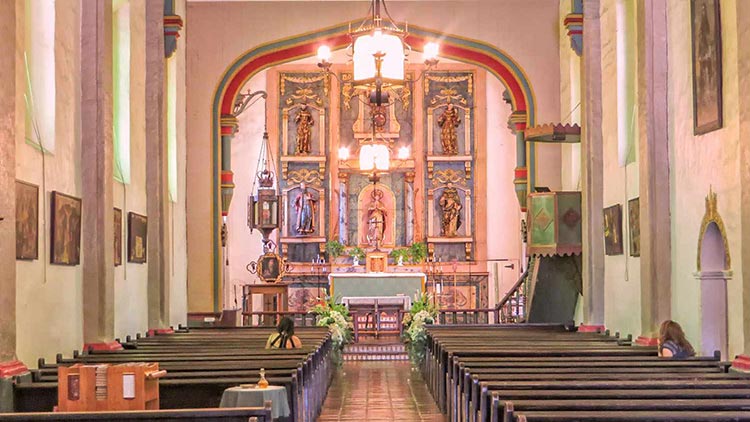 Historic San Gabriel Mission with bell tower, arched windows, and a bright blue sky.