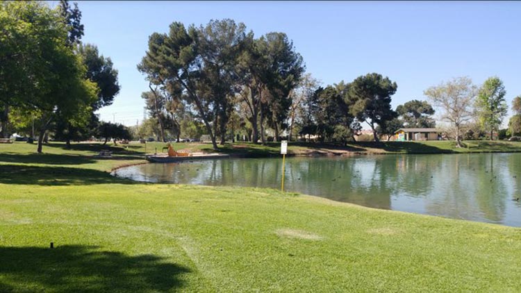 Scenic view of Whittier Narrows Recreation Area with a calm lake and green landscape.